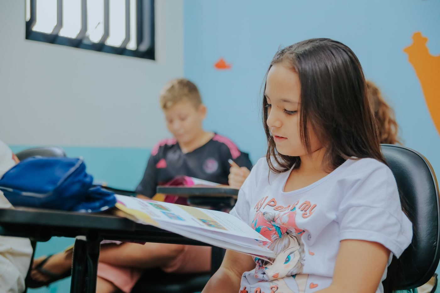 Aluna da turma Kids lendo a apostila